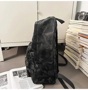 Side view of camouflage backpack with side pockets and books on white background