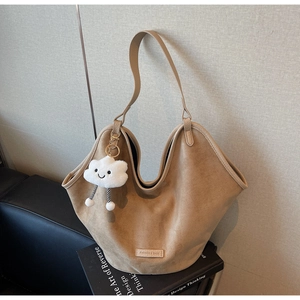 Detail of camel suede tote bag with a cloud charm and fashion label on the side