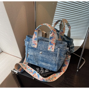 Detail of bohemian denim tote bag featuring floral embroidered handles and adjustable strap