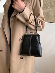 Vintage black leather shell handbag with metal clasp worn with a khaki trench coat