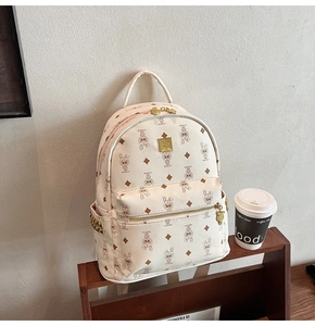 Detail view of cream backpack featuring cartoon rabbit prints and gold metal studs decoration