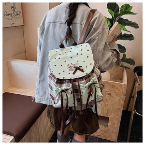 Detail of a plaid backpack with mint green pockets and brown silk bow decorations