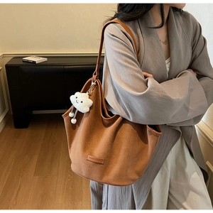 Detail view of large caramel tote bag with plush cloud pendant and fashion label