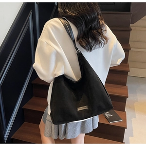 Macro di una borsa tote nera opaca con logo in metallo argento e tracolla regolabile