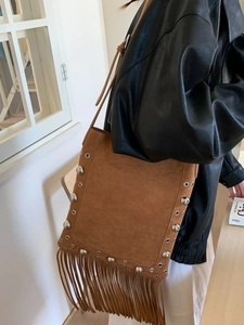 Vintage brown suede fringe shoulder bag with silver studs and adjustable strap on a model
