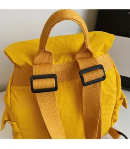 Primer plano de mochila de nailon amarillo con correas ajustables y detalle de asa superior