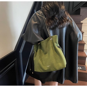 Vue détaillée du sac seau en daim vert foncé avec bandoulière chaîne et cordon
