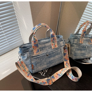 Detailed texture of blue denim tote bag with colorful floral embroidered straps