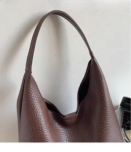 Detail shot of brown lychee grain leather tote bag with unique wavy top edge and wide strap