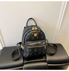 Close-up of black rabbit print leather backpack with gold studs on a textured bench
