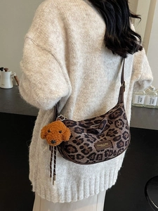 Leopard print crescent hobo bag with plush poodle charm and brown leather strap