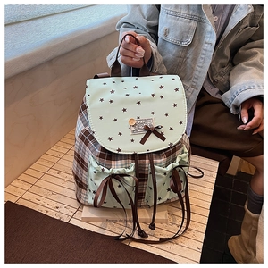 Detail of a plaid backpack with green star pockets and decorative bow knots in natural light