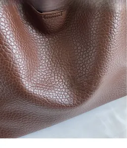 Detailed close-up of dark brown pebble grain faux leather texture and soft material finish