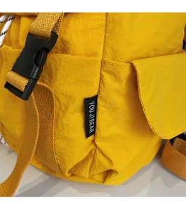 Primer plano de tela de nailon amarillo con etiqueta de marca negra y hebilla