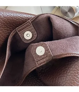 Close-up of a brown leather tote bag featuring a high-quality magnetic snap closure