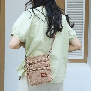 Brown corduroy crossbody bag with multiple zip pockets and adjustable strap on a model