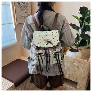 Detail view of plaid school backpack with star patterns and bow accents for women