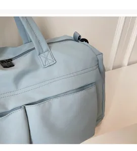 Close-up of light blue travel bag featuring waterproof fabric and reinforced handles