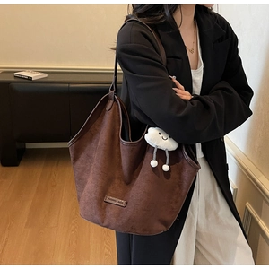 Detail of vintage brown suede tote bag with a cute white cloud plush pendant accessory