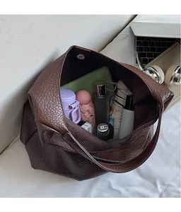 Detail view of spacious dark brown lychee textured tote bag with magnetic metal closure