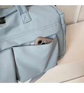 Detail of the outer storage pocket on a blue travel bag holding a mobile phone
