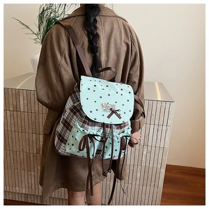 Detail showing the brown plaid and mint green backpack with bow and star patterns