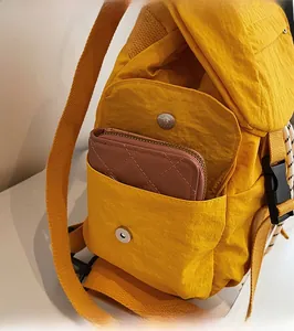 Detalle del bolsillo lateral de la mochila de nailon amarillo con hebilla de metal y cartera