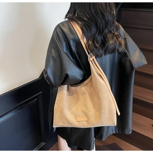 Dettaglio della borsa tote in pelle scamosciata marrone con tracolla e etichetta in pelle goffrata