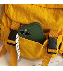 Detalle del bolsillo frontal de una mochila de nailon amarilla con un móvil