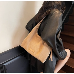 Dettaglio della borsa tote in camoscio color cammello con lacci decorativi e finiture