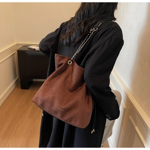 Détail du sac seau marron mat avec bandoulière tressée en cuir et chaîne argentée