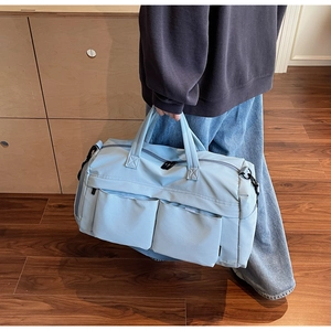Detail of light blue travel bag showing front flap pockets and durable nylon fabric
