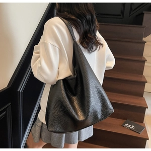 Detail of large black tote bag featuring premium pebble grain leather and soft texture