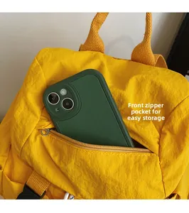 Detalle del bolsillo frontal con cremallera en la mochila de nailon amarillo para guardado