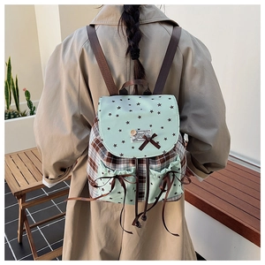 Detail of green plaid backpack featuring star patterns, cute bow and wooden button