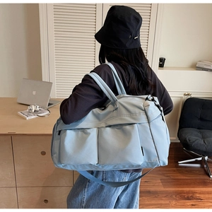 Light blue travel bag with multiple front pockets shown in a cozy lifestyle setting