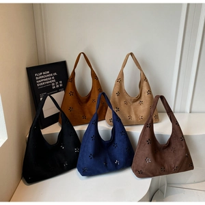 Detail of five colored hollow out faux suede hobo tote bags displayed on white pedestals