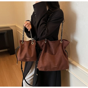Détail d'un ensemble de sacs seaux en daim marron avec logo doré et chaînes en métal