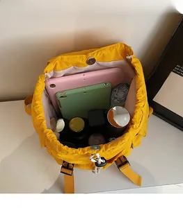 Internal view of high-capacity yellow drawstring backpack showing laptop and accessories