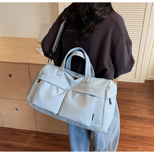 Close-up of light blue travel bag with dual front pockets and durable nylon fabric texture