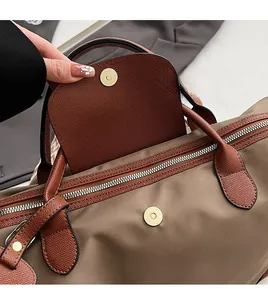Detail of khaki nylon tote bag with brown leather trim and silver metal zipper closure