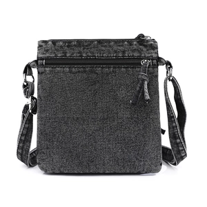 Detail of vintage washed denim crossbody bag showing front zipper pocket and fabric texture