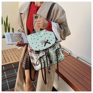 Outdoor street style shot showing the side view of the green plaid backpack on a model