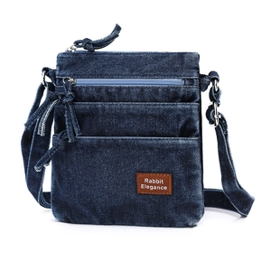 Detail of vintage blue denim crossbody bag with multiple zip pockets and leather logo