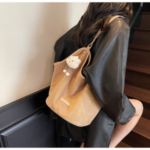 Detail of tan suede tote bag with plush cloud charm and stitched leather label
