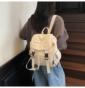 Detail of cream casual backpack showing dual buckle straps and woven drawstring cord