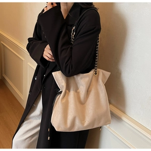 Détail d'un grand sac seau en daim beige avec cordon de serrage et bandoulière chaîne