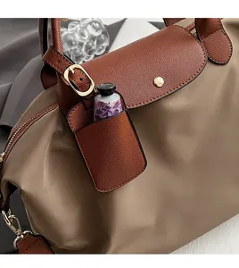 Detail of nylon handbag with leather flap and external card pocket showing cream storage