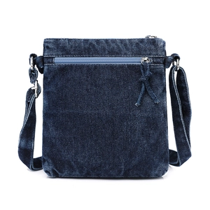 Detail of vintage blue washed denim crossbody bag featuring textured fabric and front zipper
