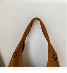 Detail of dark brown suede tote bag featuring reinforced handles and floral laser cutouts